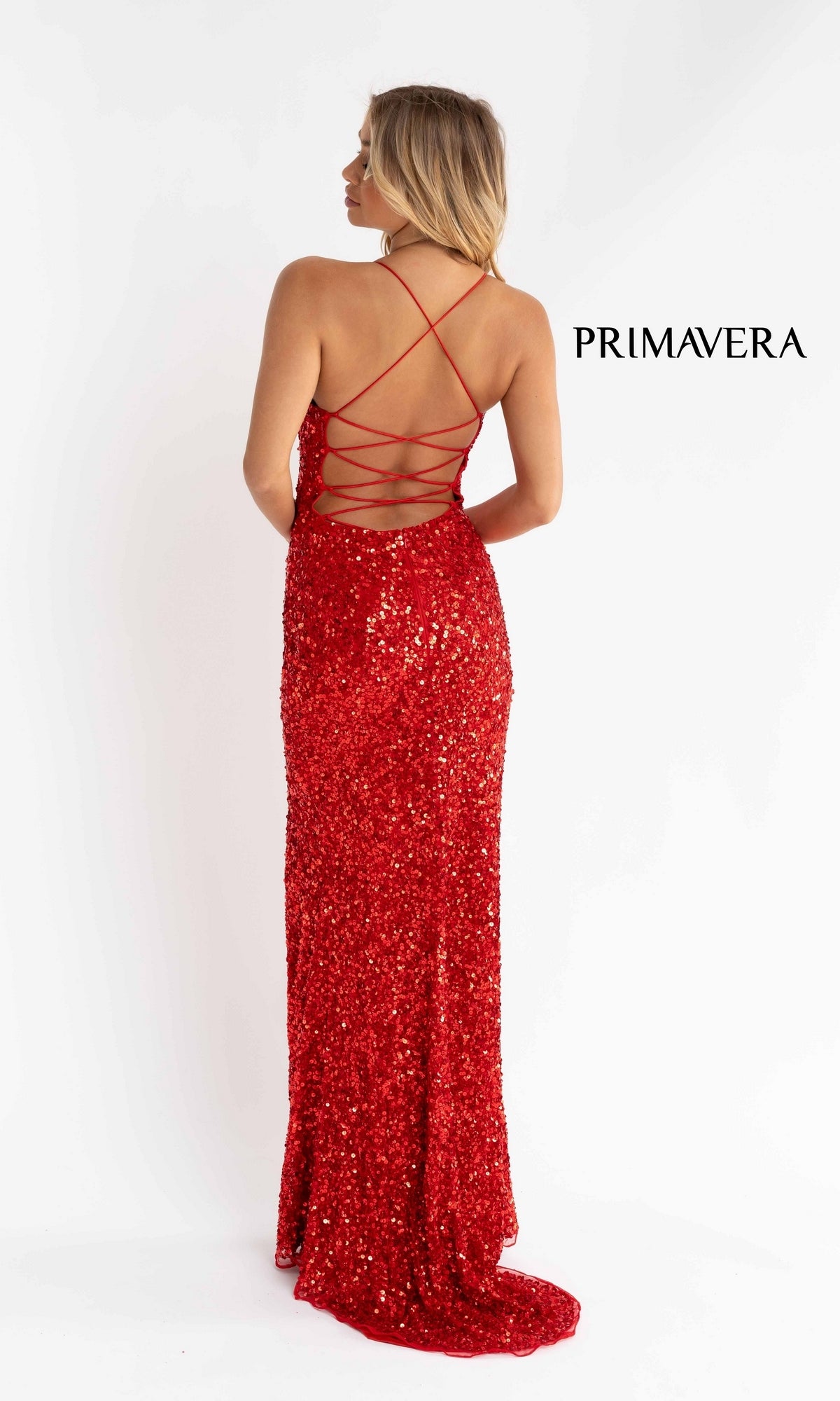 A woman in the Open Back Bold Long Sequin Prom Dress 3290D, featuring crisscross straps and a stunning open back, stands facing away from the camera. The word